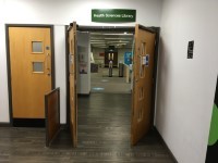 The entrance to the Health Sciences Library showing double doors which have opened automatically and an entrance foyer